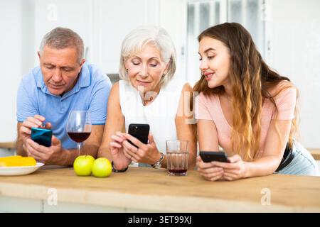 Porträt der Familie, die während des Essens im Haus telefoniert Stockfoto