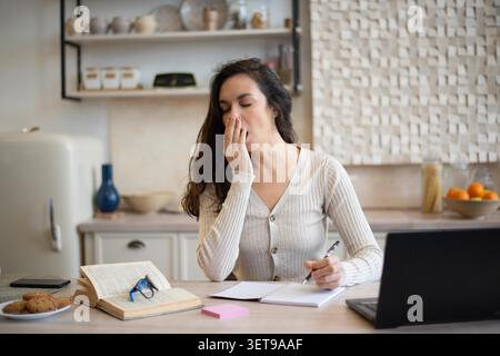 Müde Junge Kaukasische Frau Jähnt Während Der Arbeit Im Home Office, Kopierraum Stockfoto
