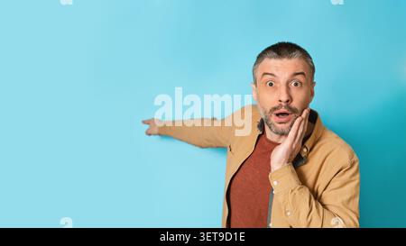Überraschter Kaukasier, Der Auf Etwas Mit Schockiertem Ausdruck Zeigt, Studio-Hintergrund Stockfoto