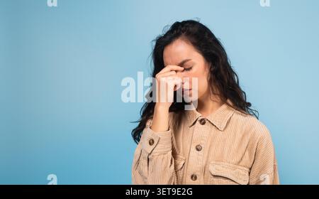 Junge Asiatische Frau, Die Sich Mit Hand Auf Der Stirn Gestresst Fühlt, Blauer Hintergrund Stockfoto