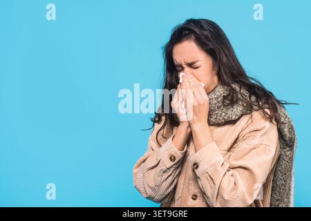 Kranke Junge Hispanische Frau, Die Gewebe Beim Niesen Hält, Blue Background Healthcare Concept Stockfoto