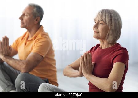 Ältere Kaukasische Paare Üben Gemeinsam Meditation Zu Hause, Entspannte Atmosphäre Stockfoto