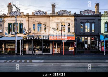 Ansicht von Ladenfronten, darunter ein Augenbrauen- und Wimpernsalon sowie eine vietnamesische Bäckerei und ein Café, in der Brunswick Street in Fitzroy, Melbourne. Stockfoto
