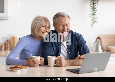 Glückliches Älteres Kaukasisches Paar Genießt Kaffee Und Kekse Zu Hause, In Der Küche Stockfoto