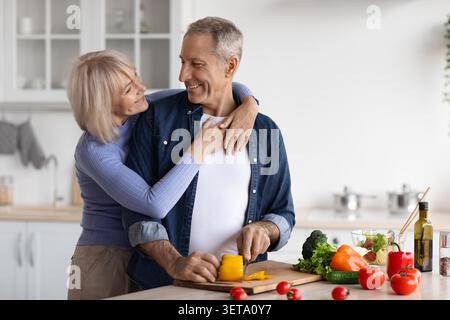 Glückliches Senior Kaukasisches Paar Kocht Zusammen In Der Küche Und Genießt Gute Zeit Stockfoto