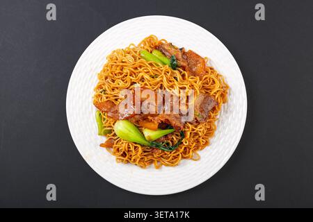 Chinesische Instant-Nudeln mit Schweinekopffleisch und Gemüse auf weißer Platte Stockfoto