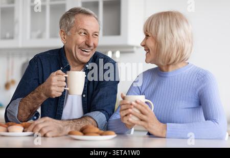 Glückliches Älteres Kaukasisches Paar Genießt Kaffee Und Unterhaltung Zu Hause, In Der Küche Stockfoto