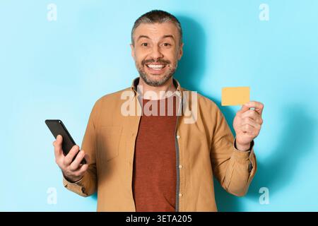 Glücklicher Mann Mittleren Alters Mit Smartphone Und Gelber Karte, Geschäftskonzept Stockfoto