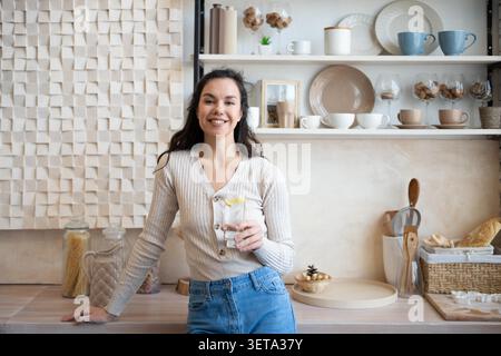 Lächelnde Junge Frau, Die Glas Wasser In Der Modernen Küche Hält, Gesundes Lifestyle-Konzept Stockfoto