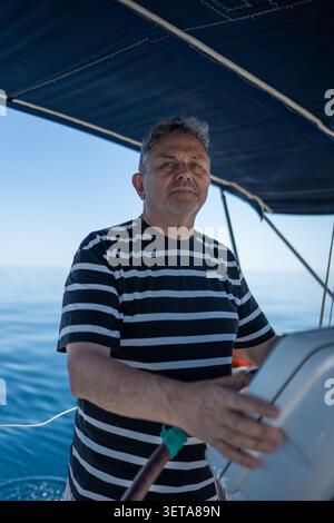 Reifer Mann, der Segelboot mit klarem Himmel steuert Stockfoto
