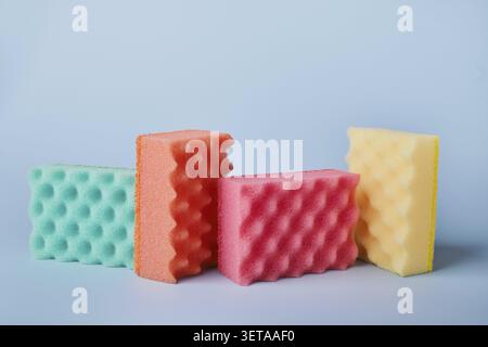 Bunte Küchenschwämme mit Seifengel und Seifenblasen auf blauem Hintergrund Stockfoto