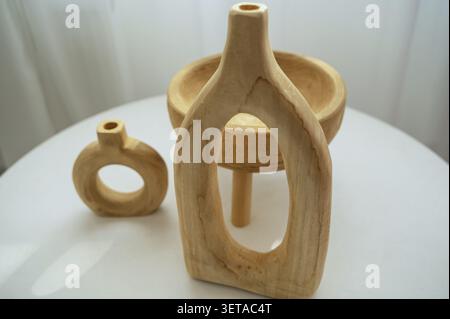 Drei hölzerne, hellbeige dekorative Töpfe. Holzgeschirr in verschiedenen Formen. Umweltfreundliches Geschirr, handgefertigte Ständer auf einem weißen Tisch. Horizontales Foto, schließen- Stockfoto