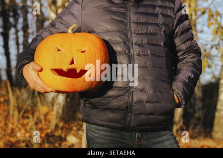 Ein großer Kürbis in den Händen eines Mannes, Nahaufnahme. Halloween-Party-Konzept. Mr. Jack oder Laterne Stockfoto