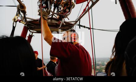 Ein ausländischer Pilot kontrolliert einen Heißluftballon, der Passagiere über der antiken Stadt Bagan in Myanmar befördert. Stockfoto