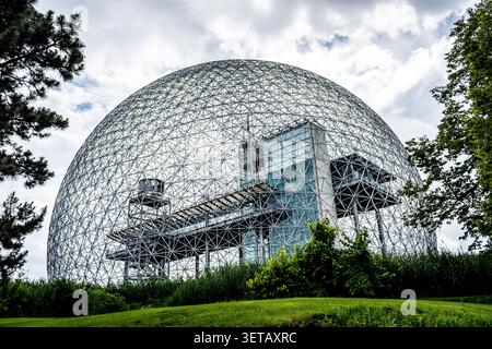 Flacher Blick auf das Biosphere Environment Museum mit seiner berühmten geodätischen Kuppelstruktur, umgeben von grünem Laub während des Tages in Montreal Stockfoto