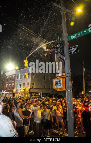 Williamsburg, Brooklyn, New York, USA - 14. Juni 2026: Blick auf einen Fan, der während der Knicks auf einer Straßenstange mit Champagner-Spray feiert Stockfoto