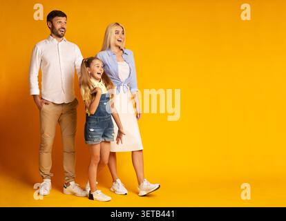 Die Familie posiert zusammen mit Joyful Expressions vor einem fröhlichen gelben Hintergrund Stockfoto