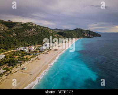 Der lange, sandige Dhermi Beach mit seinem markanten türkisfarbenen, flachen Wasser im Kontrast zum tiefblauen Meer aus der Vogelperspektive bietet einen fantastischen Blick. Entlang der Küste Stockfoto