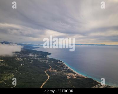Ein ausgedehntes Luftbild fängt die zerklüftete Küste der albanischen Riviera mit einem langen Sandstrand und türkisfarbenem Wasser ein Stockfoto
