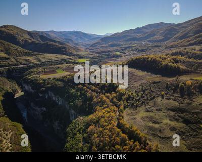 Eine weitläufige Luftlandschaft zeigt sanfte Hügel, die von einer Mischung aus grünen und herbstfarbenen Bäumen bedeckt sind, mit einem tiefen Flussschlucht, der sich durch die schlängelt Stockfoto
