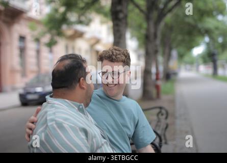 Zwei Männer teilen sich einen glücklichen Moment auf einer Stadtbank Stockfoto