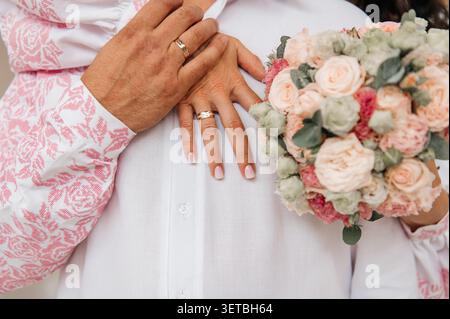 Eine Nahaufnahme der Hände eines frisch verheirateten Paares mit ihren eleganten goldenen Eheringen. Stockfoto