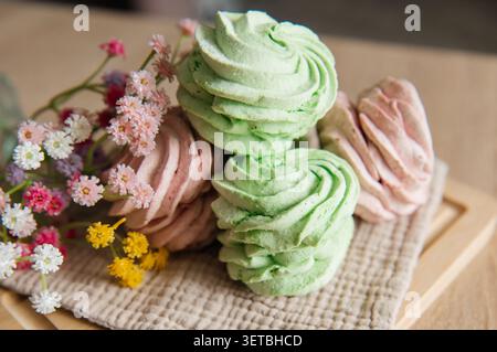 Eine wunderschöne und appetitliche Nahkomposition mit hausgemachten grünen und rosa zephyr Marshmallows, die auf einem rustikalen Holzbrett angeordnet sind. Stockfoto