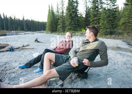 Glückliches Paar, das sich draußen in den Campingstühlen entspannt Stockfoto