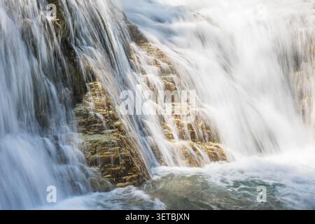 Das Wildwasser stürzt über goldene Felsstufen Stockfoto