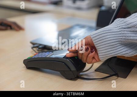 Der Kunde bezahlt für den Service mit kontaktloser Kreditkarte an einem POS-Terminal. Stockfoto