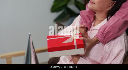 Asiatische Mutter erhält rote Geschenkbox von Kind zu Hause zur Muttertagsdankung Stockfoto
