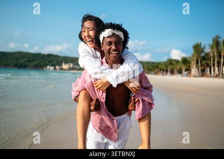 Reines Glück. Ein junges, vielseitiges, multiethnisches Paar genießt jeden Moment ihres tropischen Urlaubs Stockfoto