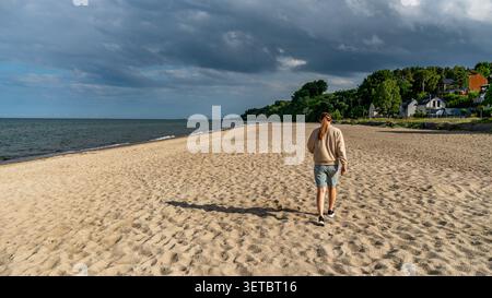 Junge Frau, Die Entlang Des Ostseestrandes Unter Dramatischen Sturmwolken Läuft Stockfoto