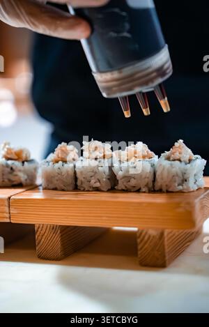 Der Koch bespritzt Sojasauce auf Sushi auf hölzernem Geta-Board, Malediven Stockfoto