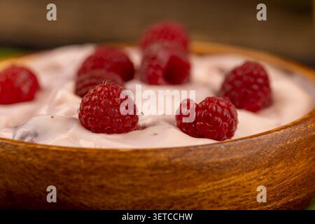 Rosa Milchjoghurt mit wilden Himbeeren, gesunder Joghurt mit roten Himbeeren auf dunkler Küchenoberfläche Stockfoto