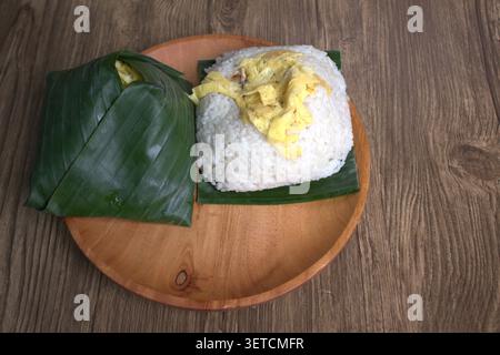 Uduk-Reis (Nasi-Uduk) in Bananenblättern gewickelt, aus denen aromatischer Reis hergestellt wird, ist ein traditionelles Essen in Indonesien, das normalerweise in traditionellen Restaurants serviert wird Stockfoto