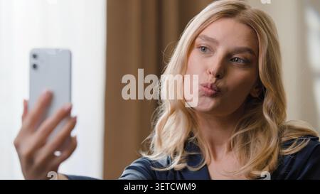Attraktive glückliche weiße Frau Influencer mit Handy machen Selfie Foto Bilder Verwöhnen Küssen lächeln für Video Live Inhalt schön Stockfoto