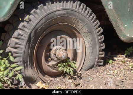 Ein alter verlassener Oldtimer mit einem rostigen Rad und Reifenpannen Stockfoto