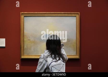 Frau mit Rucksack, die ein stimmungsvolles Landschaftsbild in den National Galleries of Scotland, Edinburgh, Schottland, beobachtet. Stockfoto