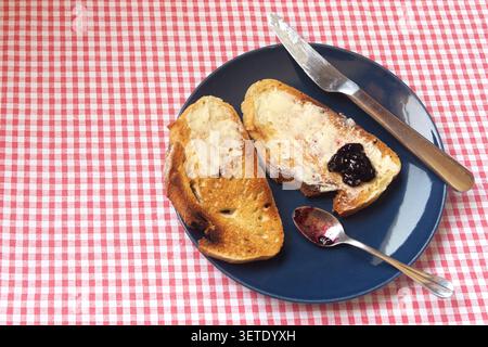 Scheiben geröstetes hausgemachtes Brot mit Butter und Heidelbeermarmelade. Stockfoto