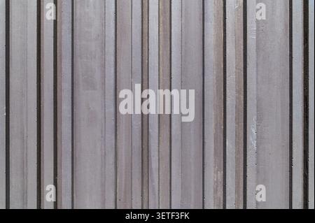 Gerillte Betonwandstruktur mit vertikalen Linien. Moderner minimalistischer architektonischer Hintergrund mit dunkelgrauer gerippter Steinoberfläche mit Streifen. Stockfoto