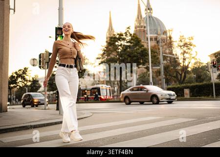 Stilvolle Frau, die in Wien selbstbewusst auf einem Kreuzweg läuft Stockfoto