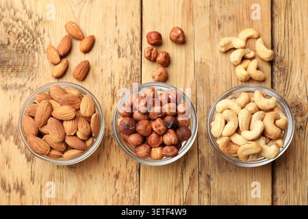 Verschiedene Nussarten in Schüsseln auf Holztisch, flach gelegt. Veganer Protein Snack Stockfoto