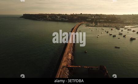 Aus der Vogelperspektive auf die Mole und den Hafen in Brixham mit Booten, die im Yachthafen bei einem sanften Sonnenuntergang vor Anker liegen, Brixham, England, Großbritannien. Stockfoto