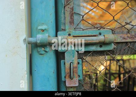 Nahaufnahme alter rostgrüner Metallschieberriegel am Kettenglied-Zaun Stockfoto