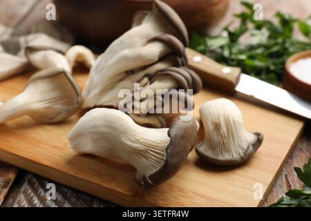 Frische Austernpilze und Petersilie auf Holztisch, Nahaufnahme Stockfoto