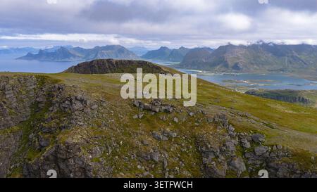 Atemberaubende alpine Landschaft der Lofoten Inseln mit felsigen Gipfeln, grüner Tundra und dramatischen Küstenfjorden mit Bergen und Stockfoto