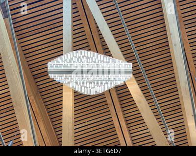 Ein moderner Kristalllüster hängt an der Holzlattendecke des schottischen Parlamentsgebäudes in Holyrood, Schottland. Stockfoto