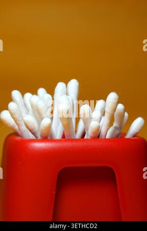 Ohrenreiniger – Ein Haufen weißer Baumwollknospen in einem roten Behälter Stockfoto
