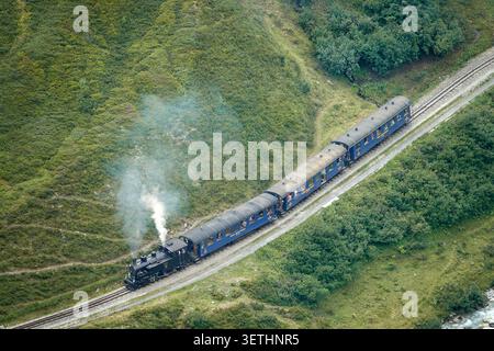Aus der Vogelperspektive der historischen Dampfbahn Furka Bergstrecke, die durch die üppig grünen Berghänge in Aarau, Aargau, Schweiz fährt. Stockfoto